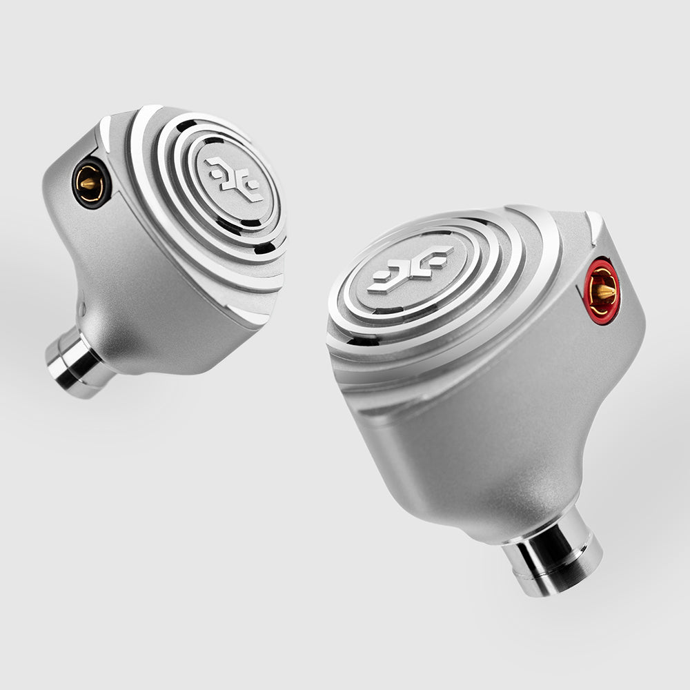Both shells of the Elysian Acoustic Labs Pilgrim — silver CNC-aluminium with tiered concentric faceplates